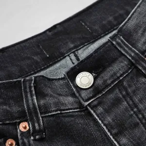 Macro view of premium metallic brand button and rivet details on black denim jeans