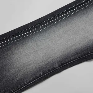 Macro detail of dark grey washed denim fabric featuring elegant rhinestone embellishments