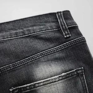 Detail shot of distressed black denim jeans waistband and back pocket stitching
