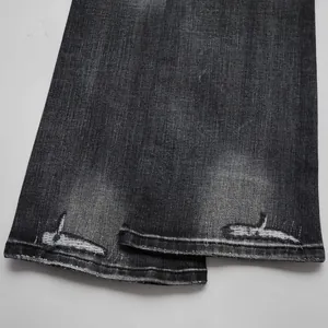 Detailed close-up of dark washed denim flare pants hem with distressed edges