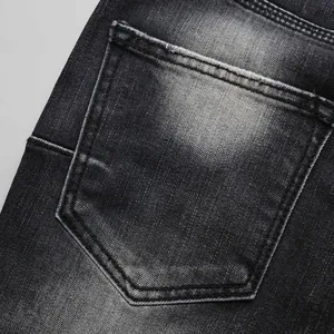 Close-up detail of the back pocket on black washed denim jeans featuring vintage fading