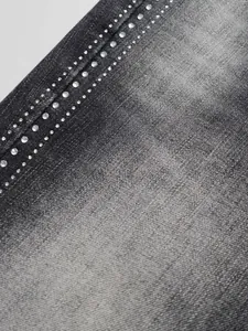 Detailed close-up of grey denim fabric with sparkling rhinestone trim for high street flare jeans