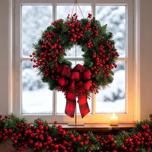 Christmas wreath with artificial red berries and red black plaid bow on window