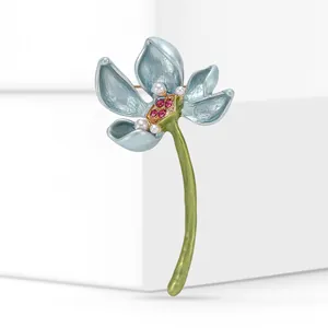 Close-up of blue enamel lotus brooch with pearls and pink crystals on a white background.