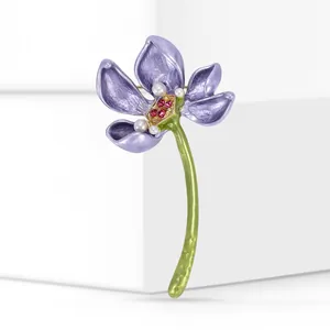 Detailed view of an elegant purple enamel lotus brooch with pearls and red crystals.