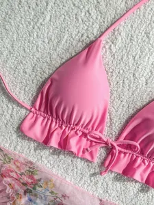 Close-up detail of a pink ruffled bikini top with adjustable front ties and ruffles