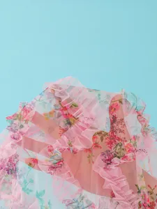 Close-up detail of sheer pink floral print mesh beach cover-up with elegant ruffle edges