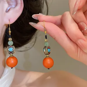 Close-up of retro Chinese style dangle earrings with large orange resin beads