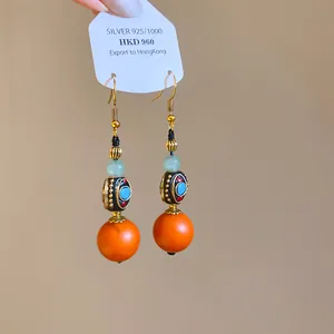 Close-up detail of ethnic style resin drop earrings with orange beads and S925 silver hooks
