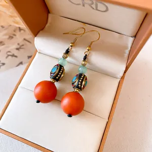 Close-up of ethnic style resin drop earrings with orange beads in a jewelry box