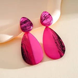 Close-up of pink resin teardrop earrings with artistic ink-wash marble texture