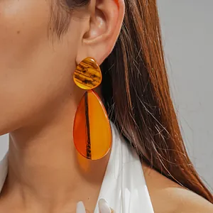 Close-up detail view of amber resin water-drop earrings with marbled texture on model's ear