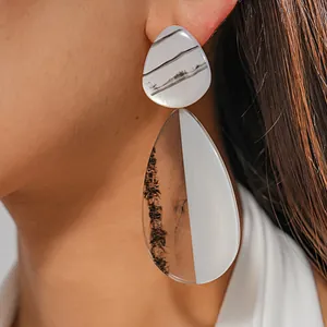 Close-up of stylish marbled resin teardrop earrings with a modern geometric design