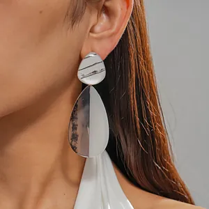 Detail view of large resin teardrop earrings with marble pattern and silver needle