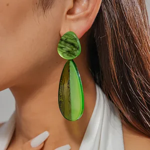 Detailed macro shot of stylish green resin water drop earrings worn by a model
