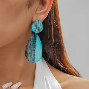 Close-up of large teal marbled resin waterdrop earrings worn by a model in detail