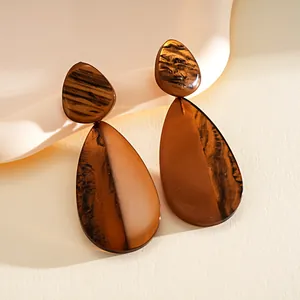 Macro view of brown resin earrings with marbled waterdrop design and glossy finish