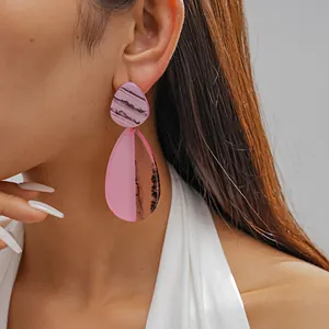 Detailed close-up of vibrant pink marbled resin teardrop earrings on a female model