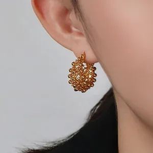 Gros plan de boucles d'oreilles créoles dorées de style vintage panier de fleurs sur modèle
