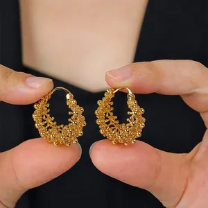 Détail d'élégantes boucles d'oreilles panier évidé en or vintage français tenues à la main.