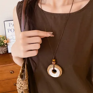 Detail view of the vintage raffia circle pendant with wooden beads and leather cord.