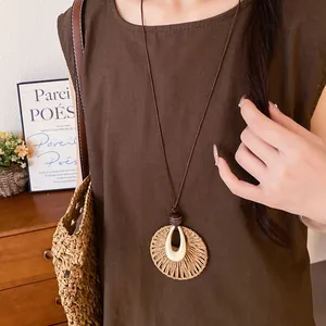 Detail of raffia pendant necklace with wood beads and leather cord in vintage style.