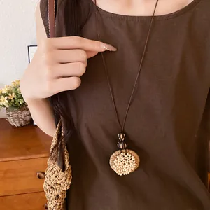 Close-up of boho raffia circular necklace with wooden beads and white seed accents.