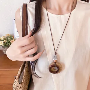 Detail view of ethnic style necklace with resin and raffia circular pendants