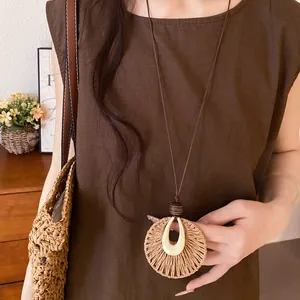 Close-up of bohemian raffia round pendant necklace with wooden beads and resin detail.