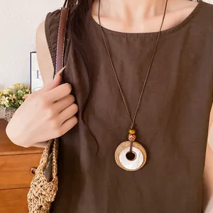 Bohemian raffia and resin circle pendant necklace on brown cord worn by a female model