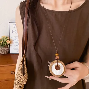 Detailed view of a vintage raffia and wooden bead pendant necklace on a brown top
