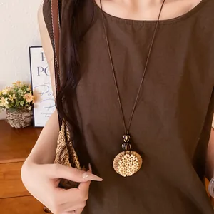 Detailed close-up of a retro ethnic style raffia and wood bead circular pendant necklace