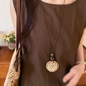 Detail view of ethnic style raffia circular pendant necklace with wooden beads