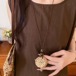 Detailed view of a bohemian raffia necklace with wooden beads on a long brown cord.