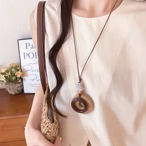 Close-up of retro ethnic raffia and resin circular pendant necklace on a long cord