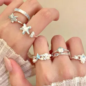 Detailopname van ringen met oceaanthema met zirkonia-zeesterren en parels aan de hand