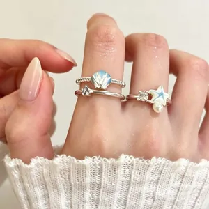 Gedetailleerd overzicht van zilveren ringen met blauwe schelp, ster, parel en zirkoon