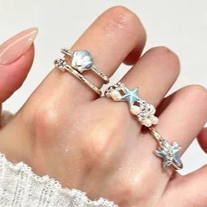 Gedetailleerd overzicht van zilveren zeester- en schelpringen met parels en blauw email