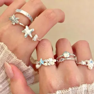 Gedetailleerd overzicht van zilveren ringen met blauwe geëmailleerde zeesterren en parels