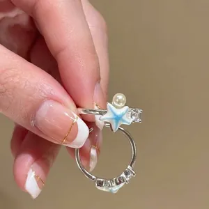 Detailopname van een zilveren zeesterring met parel, zirkonia en blauwe emaille.