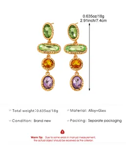 Close-up of geometric drop earrings with multi-colored crystals and gold-tone alloy