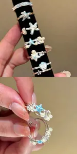 Detailweergave van blauwe zeester- en parelringen in vakantiestijl met open ontwerp.