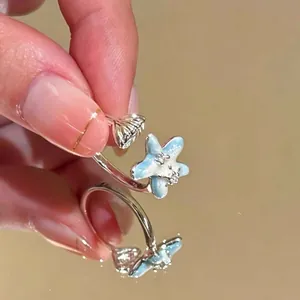 Detailopname van een zilveren zeesterring met lichtblauw emaille en zirkonia.