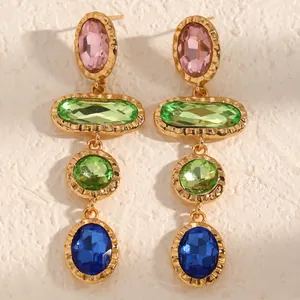 Detailed macro view of geometric colorful crystal earrings with hammered gold frames.