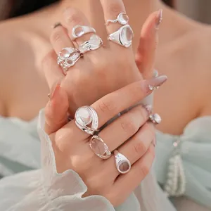 Eleganti anelli aperti minimalisti in argento con pietre di vetro ovali sulla mano della modella