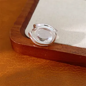 Dettaglio macro di anello minimalista color argento con ovale in vetro su vassoio