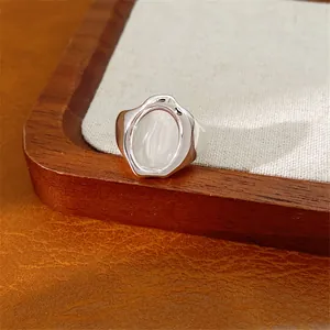 Primo piano di un anello d'argento minimalista con pietra ovale in vetro su vassoio