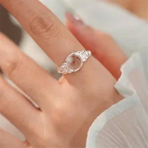 Dettaglio di un anello aperto in argento minimalista con una pietra in vetro rotonda chiara