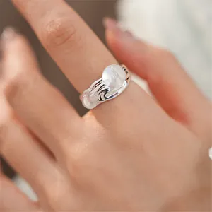Primo piano di un anello aperto in argento con pietre di vetro ovali traslucide sul dito