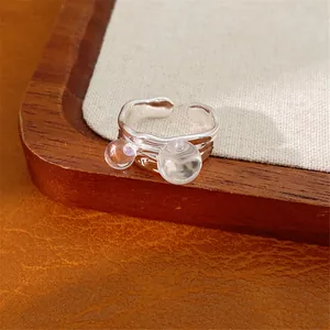 Primo piano di un anello d'argento regolabile con due sfere di vetro trasparente